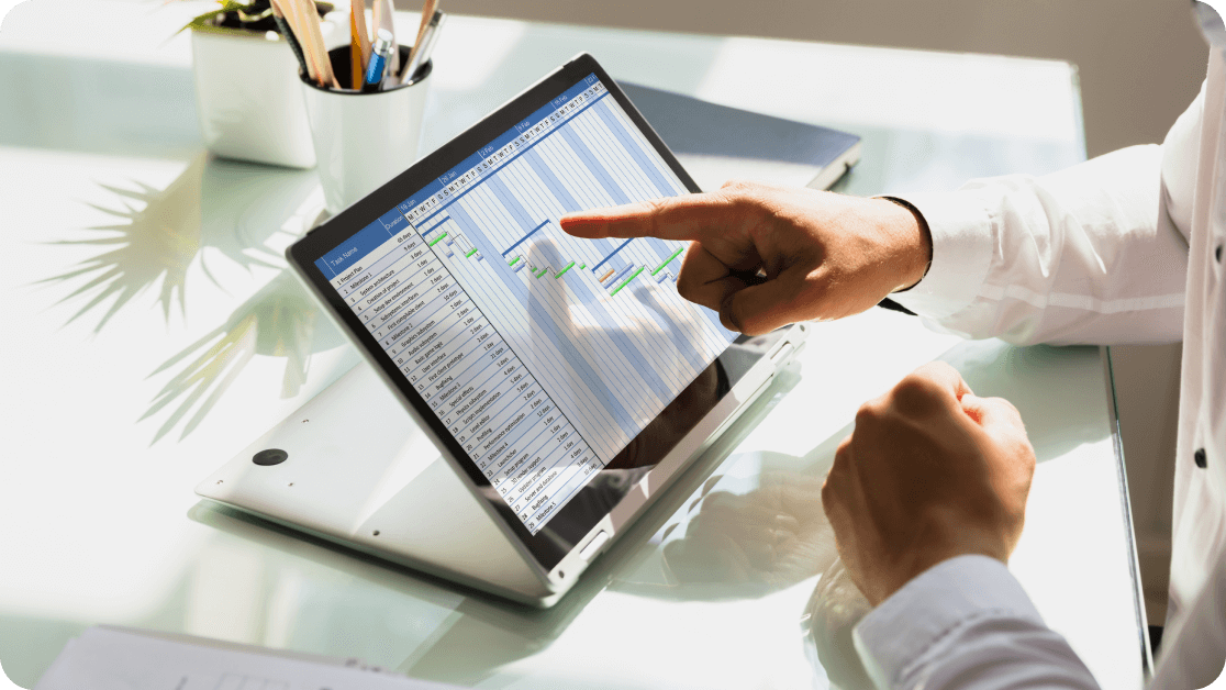 Person at a desk pointing to a spreadsheet on their tablet. 