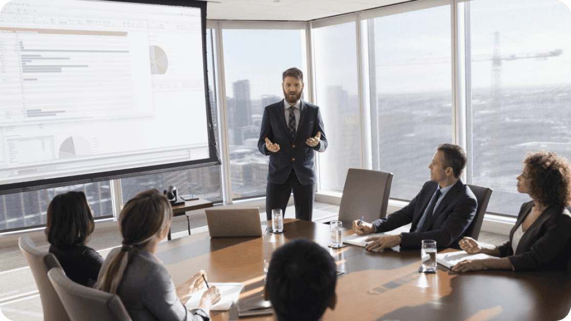 Person presenting to a group of businesspeople in a high-rise conference room. 