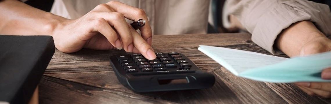 business owner reviewing paperwork, tallying sums with calculator